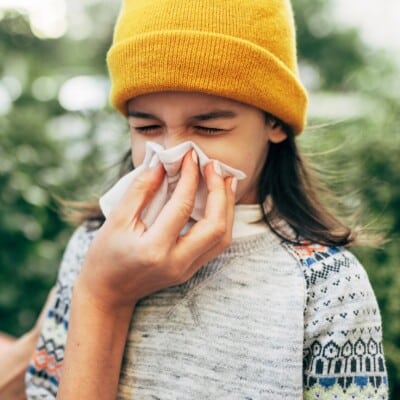 Tips to keep kids healthy during cold and flu season 6 Mother holding tissue for daughter blowing nose outside