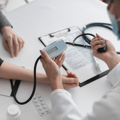 Doctor checking a patient's blood pressure, representing managing chronic conditions