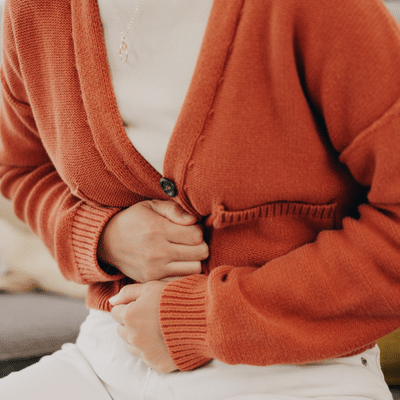 A person holding their stomach in digestive pain, representing the connection between mental health and physical health