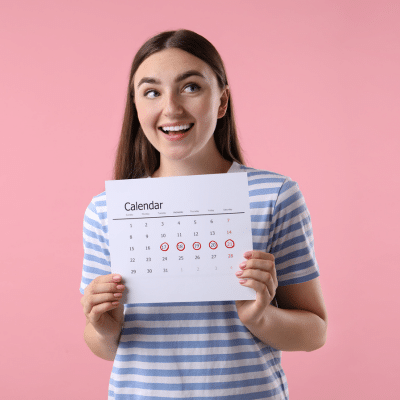 A woman holding a calendar, representing menstrual cycle