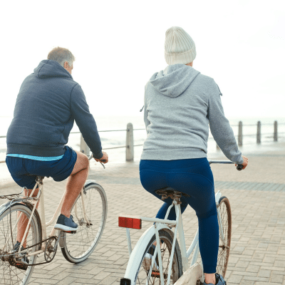 Older couple biking by the waterfront, representing cholesterol medicine vs lifestyle changes