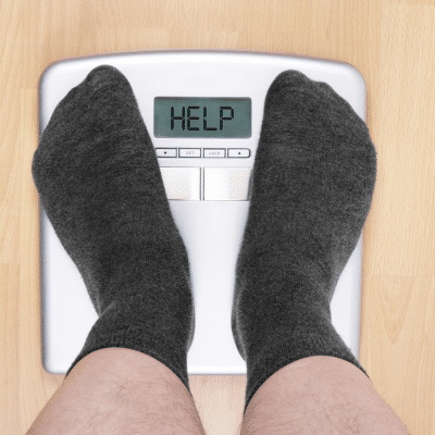 Person on scale displaying 'help', representing obesity and chronic disease